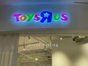 ป้ายไฟอะคริลิคหน้าร้าน Toys Rus ตัวอักษรสีเขียว ชมพู น้ำเงิน และส้ม ดีไซน์ตัวนูนมีไฟส่องสว่าง งานติดตั้งป้ายไฟในร่มคุณภาพสูง